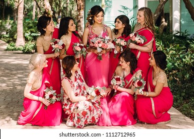 Pretty Indian Bridesmaids In Red Sari Stand Around Beautiful Bride In Pink Sari Posing Outside