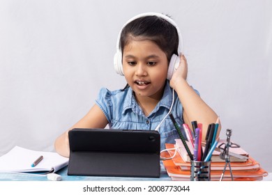 A Pretty Indian Girl Child Attending Online Class With Tablet And Headphone On White Background