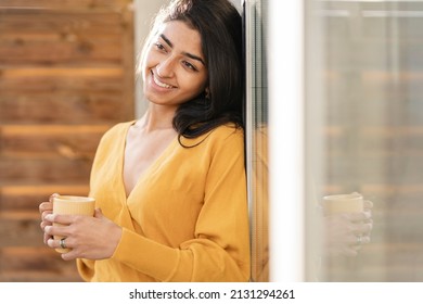 Pretty Indian Woman With Cup Of Hot Drink, At Home Window At Sunset