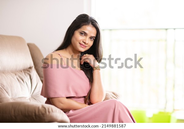 Pretty Indian young\
woman on sofa at home