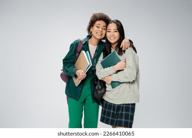 pretty interracial students with copybooks and backpacks smiling at camera isolated on grey - Shutterstock ID 2266410065