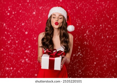 Pretty lady holding big giftbox in hands sending air kiss to handsome santa wear fluffy mini dress isolated red background - Powered by Shutterstock