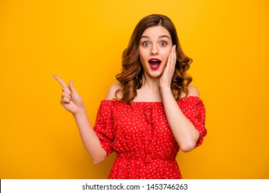 Pretty lady indicating fingers empty space showing black friday prices wear red dress isolated yellow background