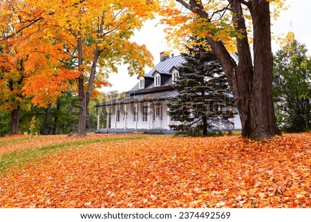 Pretty landscape with patrimonial 19th Century wooden house seen surrounded by trees with colourful foliage in the Fall in the Cap-Rouge area, Quebec City, Quebec, Canada