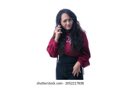 Pretty Latino Hispanic Woman With Long Thick Hair Wearing Glasses On White Background Indoors Making Expressions And Gestures, Confused, Surprised, Tense, Stressed, Perplexed,holding Her Phone With On