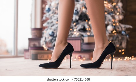 Pretty legs in beautiful high heel shoes with a Christmas gifts and New Year's Tree. New Year's party 2018. Christmas Eve.