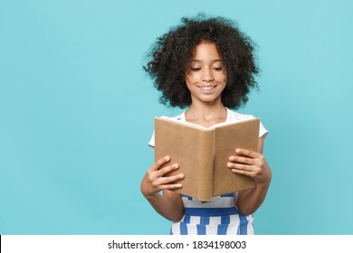 Pretty Little African American Kid Girl 12-13 Years Old In Striped Clothes Isolated On Pastel Blue Wall Background Studio Portrait. Childhood Lifestyle Concept. Mock Up Copy Space. Reading Book