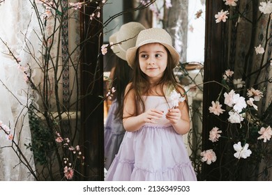pretty little Armenian girl having fun on veranda on sunny spring day decorated with flowers and Easter decor, willow branches, Easter family celebration