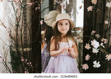 pretty little Armenian girl having fun on veranda on sunny spring day decorated with flowers and Easter decor, willow branches, Easter family celebration