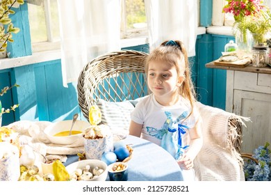 pretty little Armenian girl helps with baking for Easter on veranda on sunny spring day decorated with flowers and Easter decor, eggs, cake and willow branches, Easter family celebration