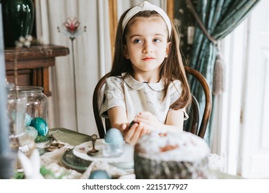 Pretty Little Armenian Girl Helps With Baking For Easter On Veranda On Sunny Spring Day Decorated With Flowers And Easter Decor, Eggs, Cake And Willow Branches, Easter Family Celebration