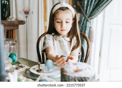 Pretty Little Armenian Girl Helps With Baking For Easter On Veranda On Sunny Spring Day Decorated With Flowers And Easter Decor, Eggs, Cake And Willow Branches, Easter Family Celebration