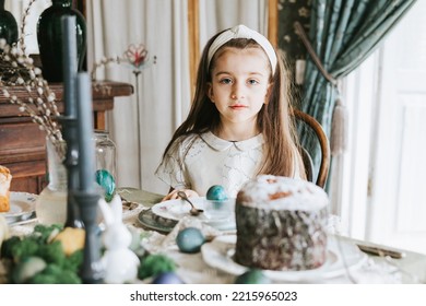 Pretty Little Armenian Girl Helps With Baking For Easter On Veranda On Sunny Spring Day Decorated With Flowers And Easter Decor, Eggs, Cake And Willow Branches, Easter Family Celebration