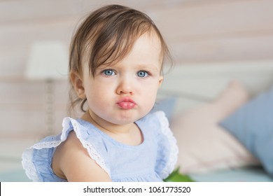 Cute Funny Baby Girl Angry Child In Home Clothes On Bed At Home View