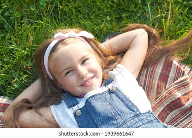 Pretty Little Child Girl With Closed Eyes Laying Down On Green Grass In Summer Taking A Nap.