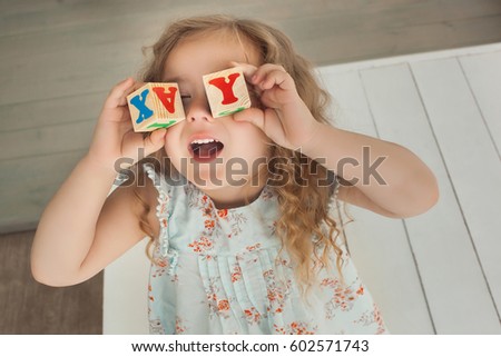 Pretty little cute girl having fun indoors. Pretty child playing with an abc cubes. Cute girl close up portrait.