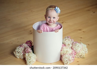 A pretty little girl in a gift box among flowers. The concept of childhood and motherhood - Shutterstock ID 2090137342