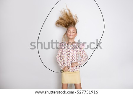 Pretty little girl jumping rope and joyfully smiles on white background. Active happy kid concept.
