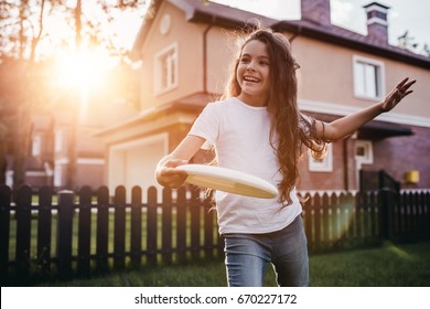 Pretty little girl is playing, having fun and smiling on the backyard on the sunset.