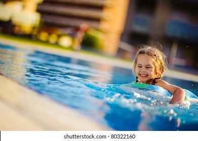 Pretty little girl swimming in outdoor pool and have a fun with inflatable circle - Powered by Shutterstock