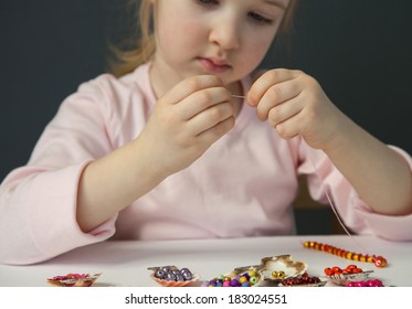 Pretty Little Girl Threading Beads And Making Bracelet