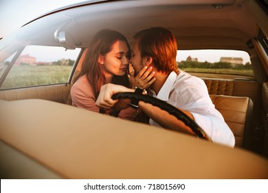 Pretty lovely couple kissing while sitting inside a retro car