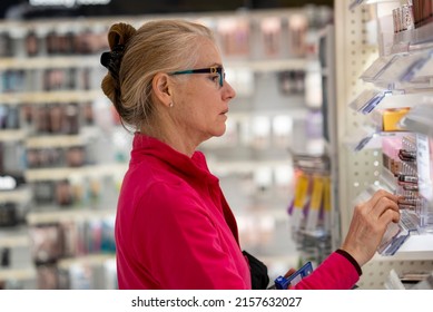 Pretty Mature Middle Age Woman Shopping For Makeup In A Bright Airy Big Box Store.