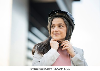 Pretty Mature Woman Putting On Bicycle Helmet When Leaving Work