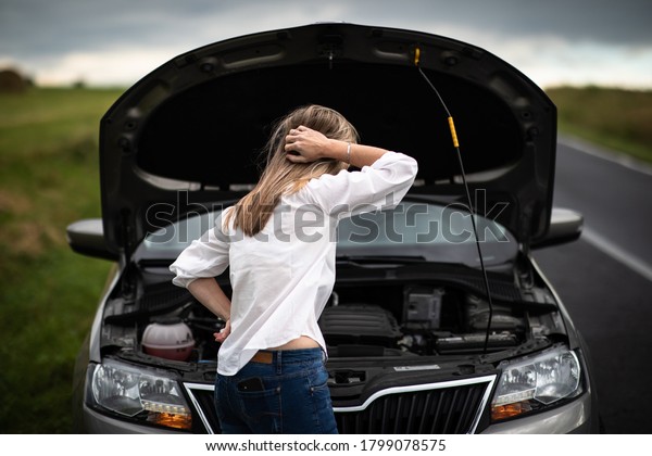 Pretty middle aged woman having car troubles -\
broken down car on the side of the road, calling the insurance\
company for assistance