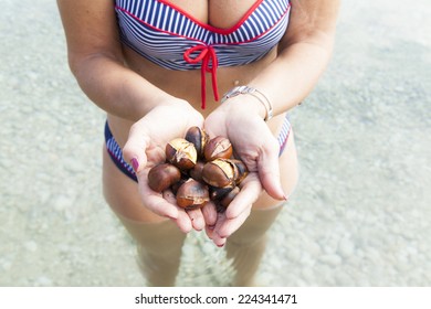 Pretty Middle Aged Woman With Roasted Chestnuts On The Sunny Beach, Whilst Standing In Sea, Wet Skin With Goosebumps 