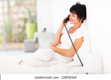 Pretty Middle Aged Woman Talking On Landline Phone On Bed