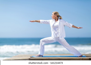 pretty middle aged woman yoga pose by the beach - Powered by Shutterstock