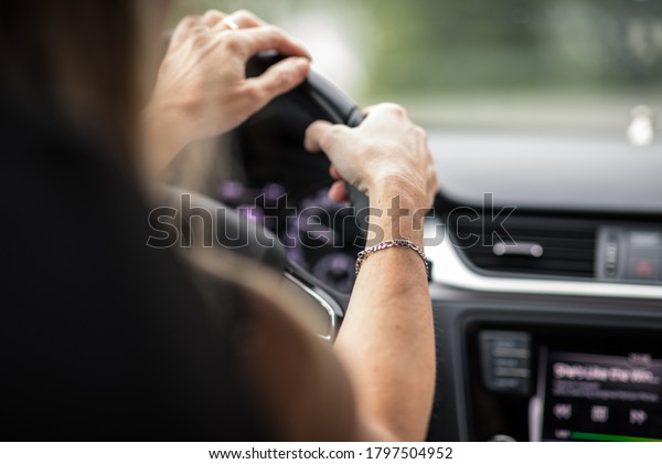 Pretty midle aged woman at the steering wheel of her\
car commuting to work