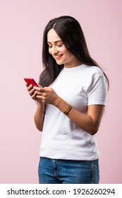 Pretty Millennial Indian Girl Isolated On Pink Studio Background Text Messaging On Cell Phone Or Using Smartphone With Wireless Connection