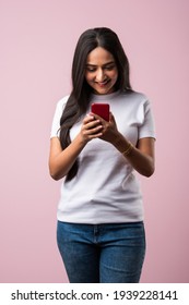 Pretty Millennial Indian Girl Isolated On Pink Studio Background Text Messaging On Cell Phone Or Using Smartphone With Wireless Connection