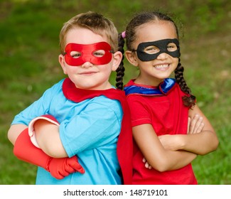 Pretty mixed race girl and Caucasian boy pretending to be superhero