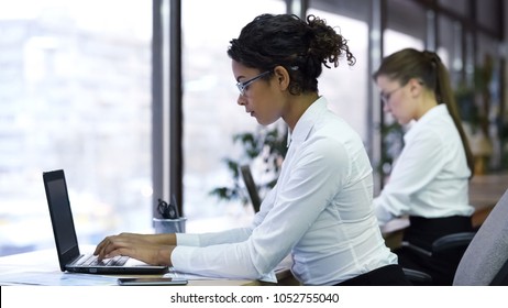 Pretty mixed-race lady typing on laptop, working for company support center - Shutterstock ID 1052755040