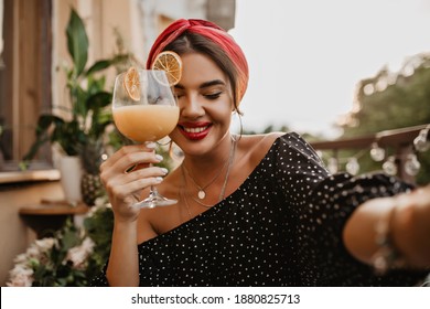Pretty modern lady with silver accessories, cute smile and bright bandana in black polka dot clothes holding cocktail glass.. - Powered by Shutterstock
