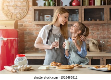 Pretty Mom And Daughter Spending Time Together At Kitchen, Eating Cupcakes And Drinking Milk, Copy Space