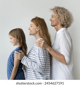 Pretty multi-generational women, little girl her young mom and older granny standing in row against gray studio wall background. Heredity, from childhood to midlife, generational bonds, family legacy - Powered by Shutterstock