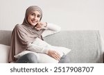 Pretty Muslim Housewife Smiling At Camera On Sofa At Home, Holding Pillow While Sitting On Comfortable Couch In Living Room, Copy Space