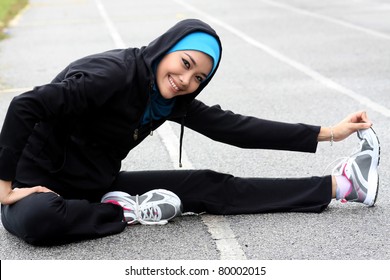 A Pretty Muslim Woman Athlete Stretching Her Body At Stadium Track