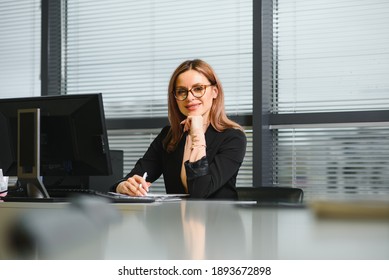 Pretty, Nice, Cute, Perfect Woman Sitting At Her Desk On Leather Chair In Work Station, Wearing Glasses, Formalwear, Having Laptop And Notebook On The Table