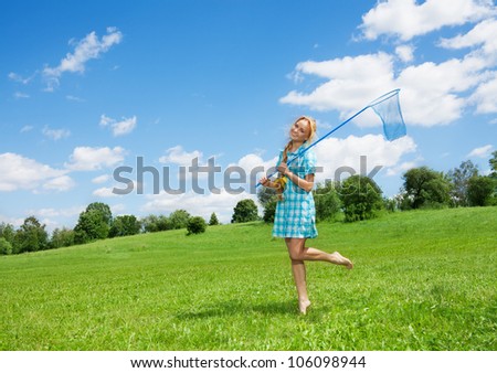 pretty nice girl with butterfly net walking on the green lawn