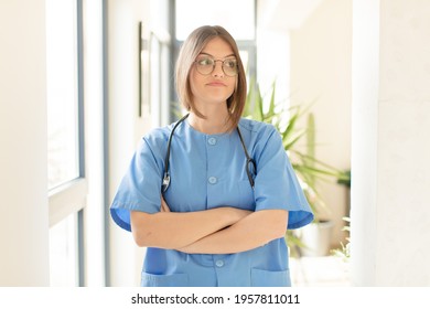 Pretty Nurse Shrugging, Feeling Confused And Uncertain, Doubting With Arms Crossed And Puzzled Look