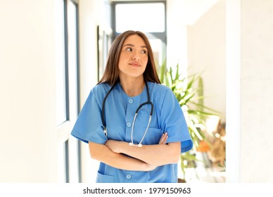 Pretty Nurse Shrugging, Feeling Confused And Uncertain, Doubting With Arms Crossed And Puzzled Look