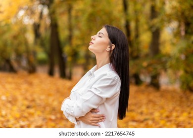 Pretty Office Worker (woman) Closes Her Eyes And Breathes Fresh Air In Autumn Park During Lunch Time, Walking Outdoors. Relaxation, Solitude With Nature. Stress Relief, Mental Health. Horizontal Plane