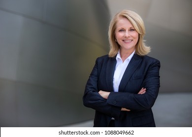 Pretty older business woman, successful confidence with arms crossed in financial building - Shutterstock ID 1088049662