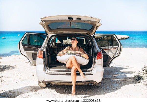 Pretty pan asian brunette with float near car trunk\
at the seaside beach