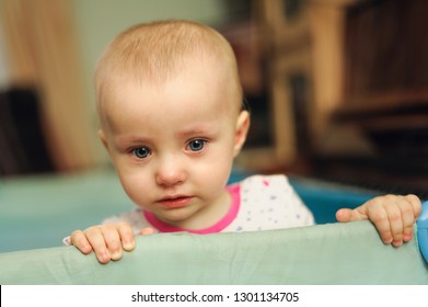 pretty pathetic sad child standing in playpen